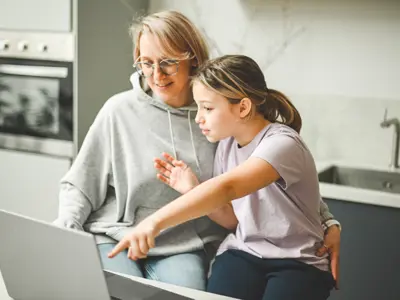 Mom and daughter reading news on laptop